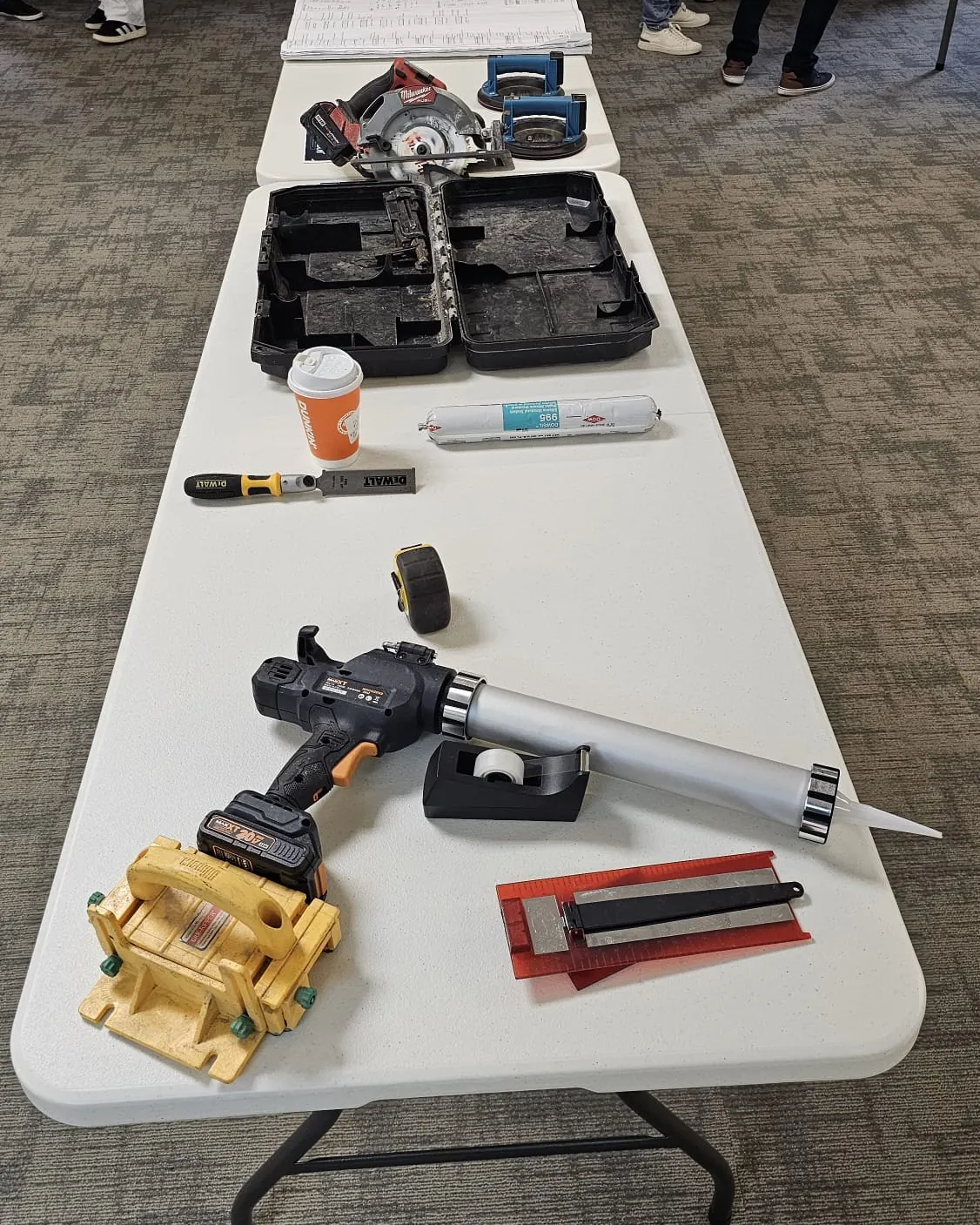 Table with a circular saw, suction cup lifters, caulk gun, sealant, chisel and tape measure