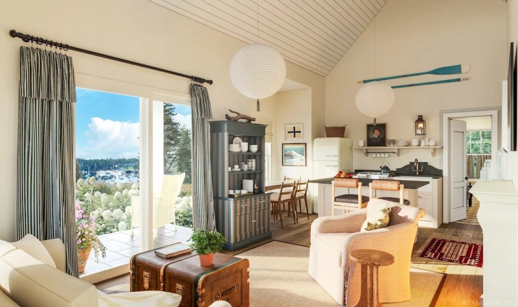 Cozy coastal-style living space with vaulted ceiling, compact kitchen, vintage decor, and large glass doors opening to a garden view